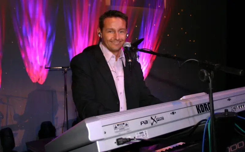 Markus Schumacher spielt auf einer Bühne Keyboard und singt