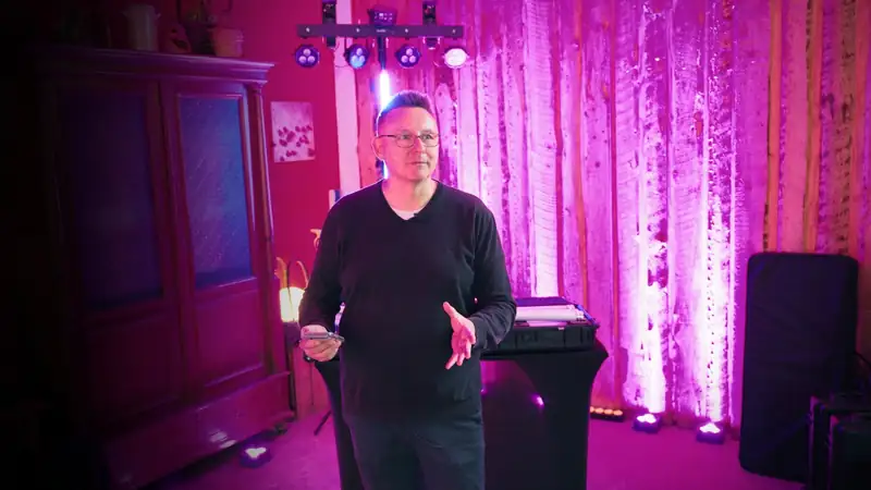 Markus Schumacher steuert das Licht per Handy, hinter ihm LED-Bar, Röhre und pink beleuchtete Wand mit Boden-Spots